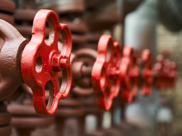 红色工业阀门在石油化工装置管道系统上的一排选择性对焦，对非对焦背景。图片下载