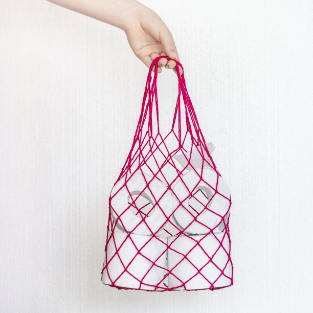 红色绳袋和一卷厕纸。消费必需品的概念、卫生、健康、抗恐慌。零浪费购物图片下载