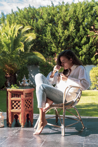 阿拉伯年轻女子与民族特征闻到薄荷阿拉伯茶在她的花园。图片下载