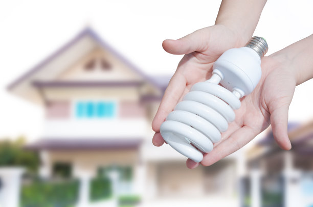 节能理念，家居背景上手持灯泡的女人图片下载