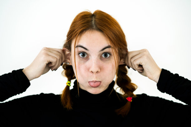 近距离的肖像有趣的女孩抱着她的耳朵与手像一只猴子。图片下载