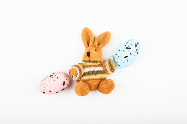 棕色毛绒野兔与复活节彩蛋在白色的背景。彩色鸡蛋点缀图片下载