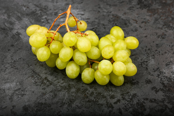 绿色的葡萄在大理石黑色背景上的照片。体积葡萄。一串绿色的葡萄藤图片下载
