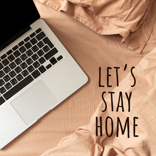 短语让我们呆在家里吧。笔记本电脑放在床上的棕色亚麻布上。图片下载