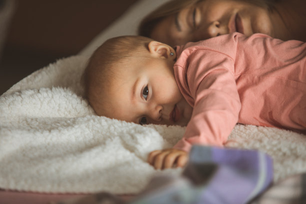 安静的小憩时间，女婴还在醒着，妈妈还在睡觉图片下载