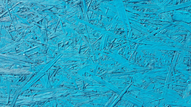 混乱的胶合板纹理在阴影的蓝色。用压碎的木屑和木屑制成的裂开的胶合板。蓝色的木制背景与复制空间。图片下载