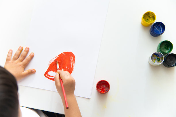 小男孩在纸上手绘。可爱的小男孩正在坐着画画。呆在家里素材图片