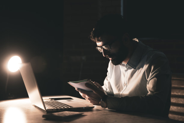 人手持记事本，桌上放着电脑图片下载