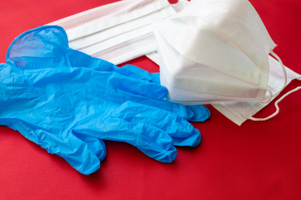 红色背景上的医用口罩和手套。图片下载