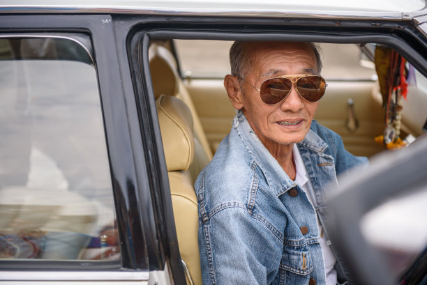 穿着牛仔夹克开着老爷车的亚洲老人图片下载
