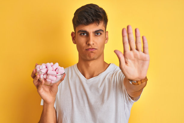 手捧棉花糖碗的年轻印度男子，手势严肃自信图片下载