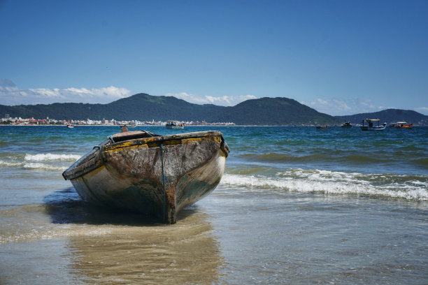 海滩在阳光明媚的日子里有海鸥，小船和沙滩上有小船搁浅在沙滩上。彩色照片图片下载