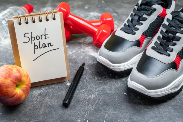 运动鞋，哑铃，苹果和一瓶水在灰色的背景。健康生活方式、运动计划、积极活动、运动和饮食的概念。运动设备图片下载