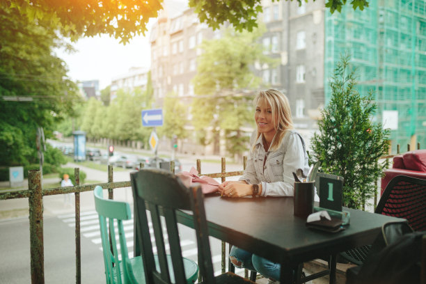 年轻女子在路边咖啡馆等待饮料和食物图片下载