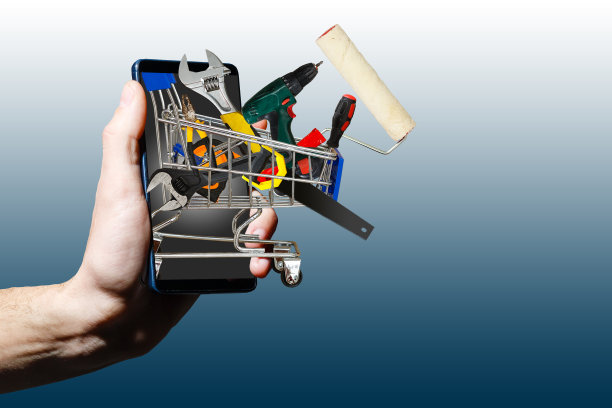 当用手机在线购物时，一个人的手拿着购物车和工具图片下载