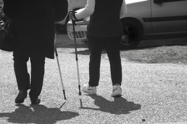 两个妇女拄着拐杖在城市街道上行走图片下载