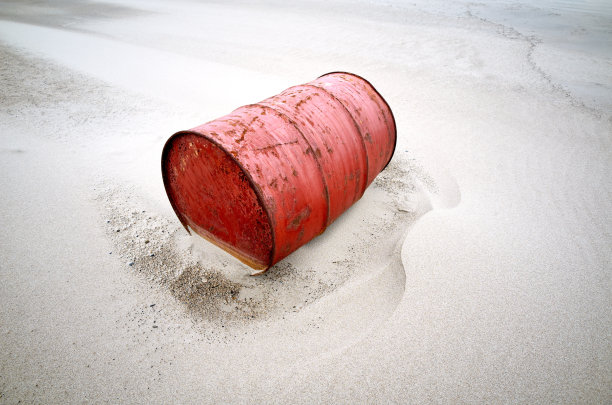 红色生锈的旧桶在沙漠的沙子图片下载
