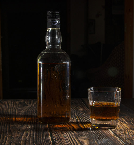 桌子上的铃上有酒。威士忌和冰块放在木桌上。加冰的玻璃杯里的威士忌。图片下载