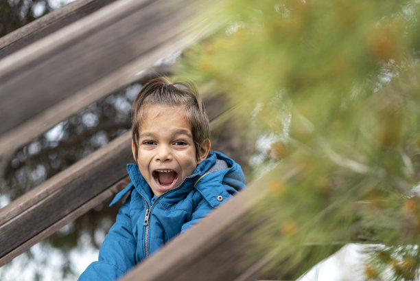 快乐的小男孩坐在木楼梯上图片下载