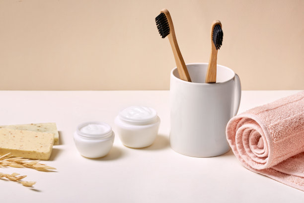 两个环保和竹牙刷在杯子，容器，奶油，肥皂和毛巾图片下载