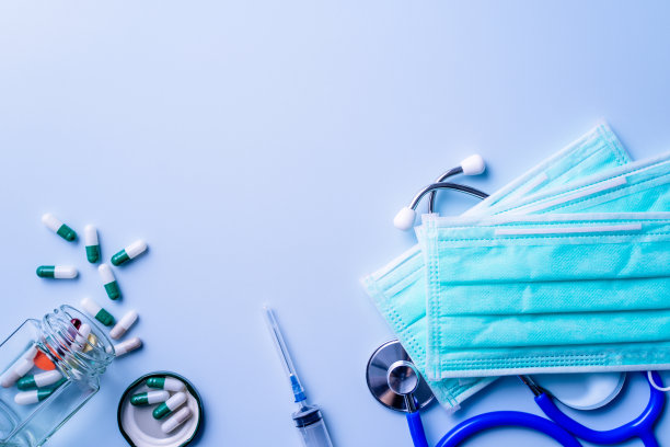 装有药片、听诊器、注射器等医疗用品的面罩在蓝色背景上隔离。图片下载