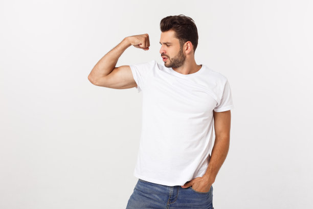 英俊的fit年轻有趣的胡子男子指着他的二头肌和微笑在白色的背景图片下载