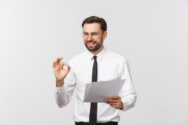 年轻的商人严肃的书写在剪贴板上，英俊的商人穿着优雅的西装和领带孤立的白色背景。素材图片