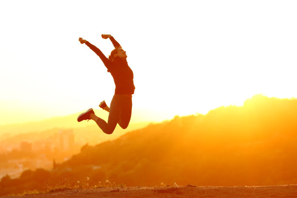 兴奋的跑步者在日落时跳跃在城市郊区图片下载