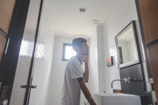 一个年轻人在浴室里看着镜子里的自己图片下载