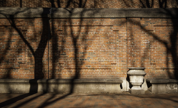 古朴的红砖墙、石凳、石花瓶和树影图片下载