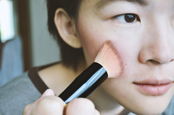 女人在脸上刷粉，柔焦照片。图片下载