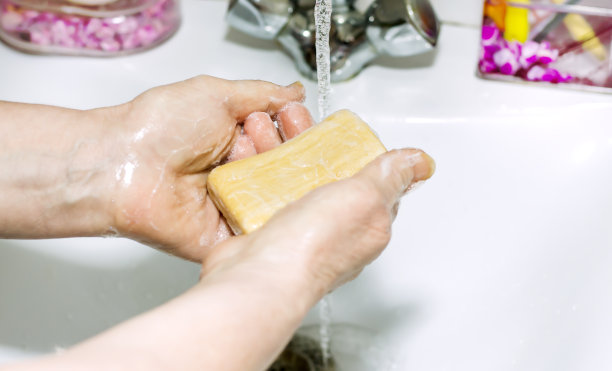 一位上了年纪的妇女用肥皂洗手，以预防病毒感染图片下载