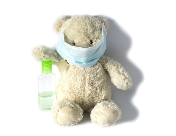 泰迪熊在医用口罩的白色背景上配有一瓶杀菌胶，为儿童提供病毒防护概念图片下载