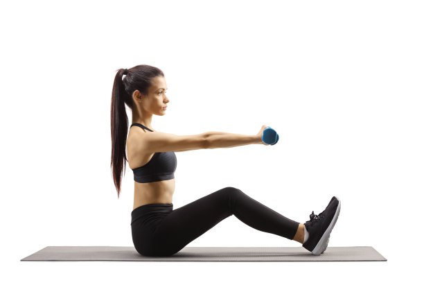 年轻漂亮的女人坐在垫子上用哑铃锻炼图片下载