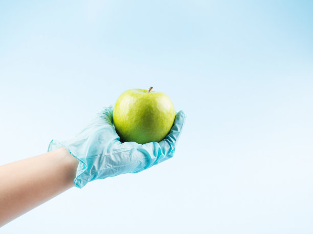 手里拿着新鲜的绿苹果，手套戴着蓝色图片下载