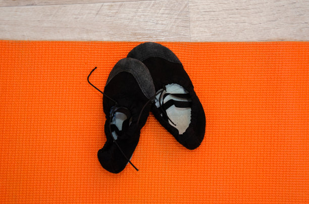 橙色运动垫上的黑色婴儿芭蕾舞鞋图片下载