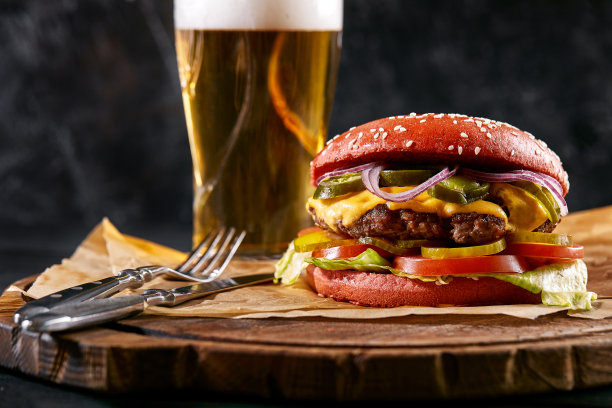 多汁的汉堡，薯条，酱汁和一杯冰啤酒在一个深色的木制背景。复制空间，快餐套餐，食物照片图片下载