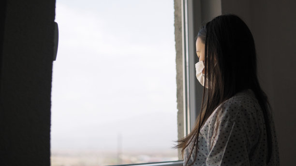患病青少年通过窗户看冠状病毒，戴口罩防护，并从疾病中康复后在家中隔离隔离图片下载