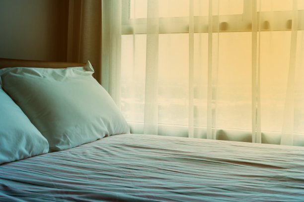 柔软的床上放着白色的枕头，粉色的床单和橙色的灯图片下载