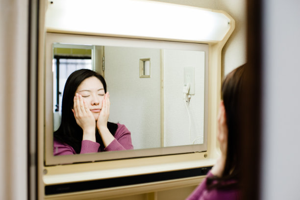 透过镜子拍摄的亚洲女性在浴室做美容护理的照片图片下载