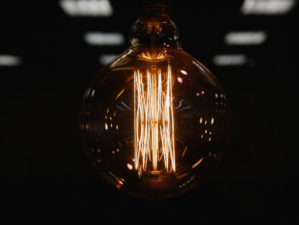 圆的白炽灯。复古风格的圆形钨丝灯。在黑暗中发光，有选择焦点的特写照片。特写镜头。黑暗的背景。散焦背景图片下载