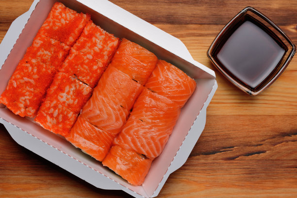 寿司卷在一个盒子和一个杯酱油在一个木制的背景，俯视图图片下载