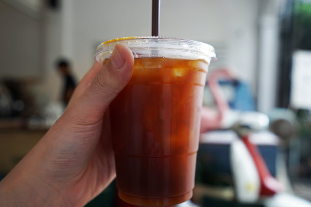 手里拿着塑料带走的一杯冰黑美式咖啡图片下载