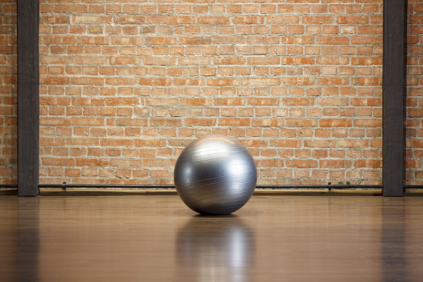 在一间有砖墙的健身室里，地板上放着一个银色的健身球图片下载