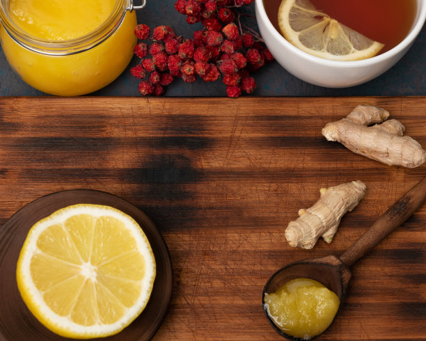 特写照片的一个深色的木制盘子周围有一个新鲜的柠檬，蜂蜜，rowanberry，生姜和一杯热茶。Immuntiy产品概念。平铺，俯视图，拷贝空间。图片下载