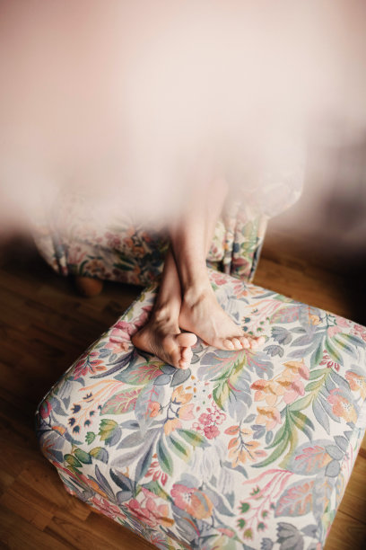 女人完美的腿蜡休息在沙发上在家。光着脚坐在沙发上图片下载