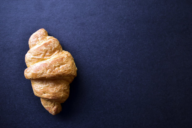 黑色背景上的黄色牛角面包图片下载