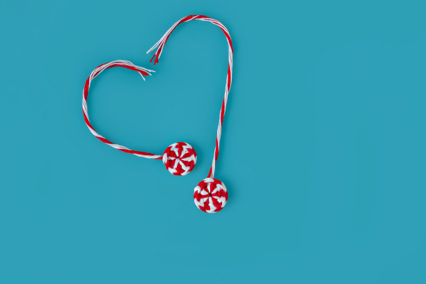 针织红白相间的圆形糖果焦糖两片，在蓝色的背景上摆出心形，概念图片下载