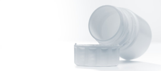 白色塑料瓶放置在接近盖子的地方，水平隔离在白色背景上。有拷贝空间的照片。图片下载