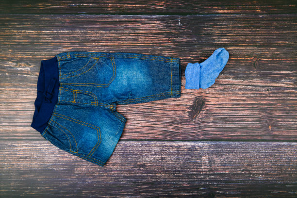 木制背景上的儿童牛仔裤。时尚的概念。服装的概念。深色木制背景。小男孩和牛仔裤。婴儿的衣服图片下载